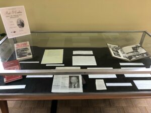 A glass exhibit case shows an archival exhibit about Paul Conkin